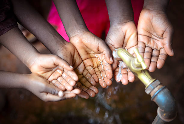 Three African children holding their hands under a tap. Symbol for the importance of water in African countries.